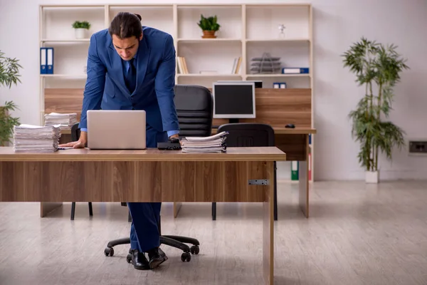 Joven empleado masculino y mucho trabajo en la oficina — Foto de Stock