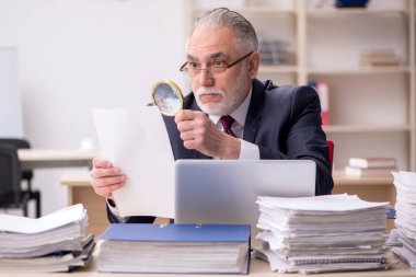 Yaşlanmış erkek çalışan ve işyerinde çok fazla iş var.