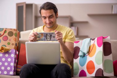 Evde bir sürü çantası olan genç bir adam var.