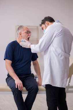 Yaşlı erkek hasta genç doktor otorhinolaryngologis 'i ziyaret ediyor.