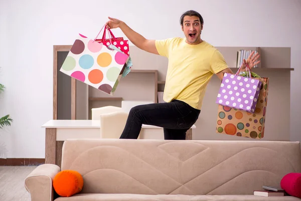 Joven con muchas bolsas en concepto de Navidad en casa —  Fotos de Stock