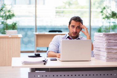 Ofisteki aşırı işten memnun olmayan genç bir erkek işçi.