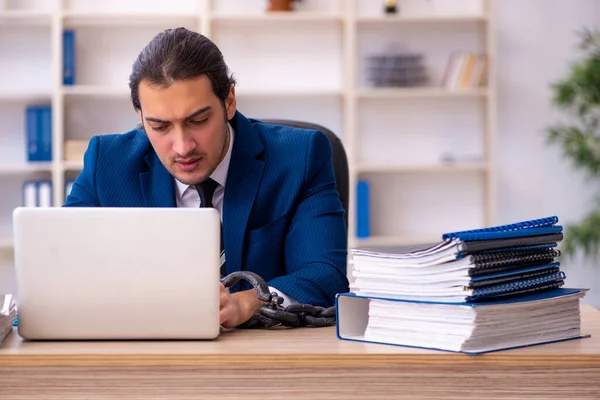 Geketende mannelijke werknemer ongelukkig met overmatig werk in het kantoor — Stockfoto