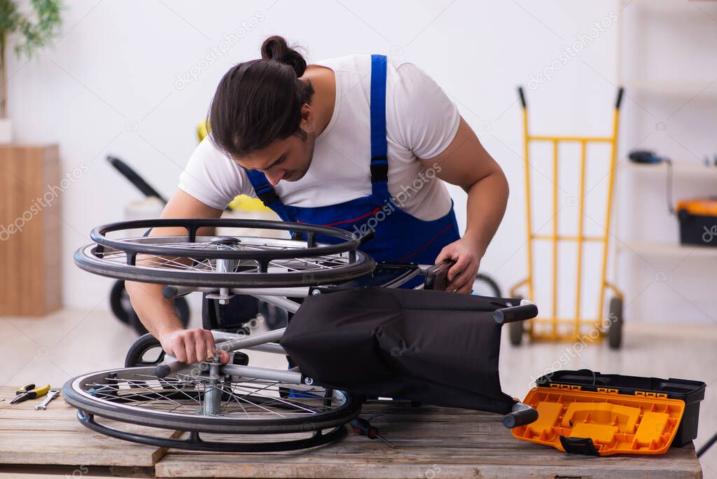 Young male repairer repairing wheel-chair indoors
