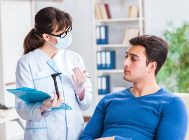 Doktor muayene sırasında hastaların kulaklarını kontrol ediyor.