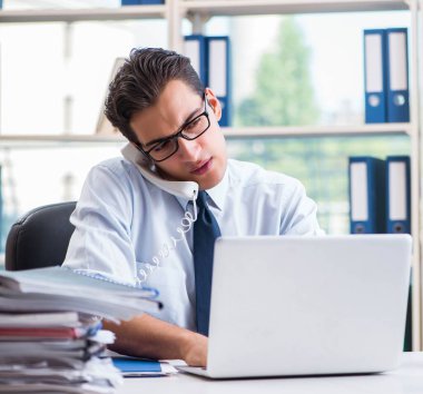 Ofiste çalışan aşırı çalışma evrakları olan bir iş adamı.