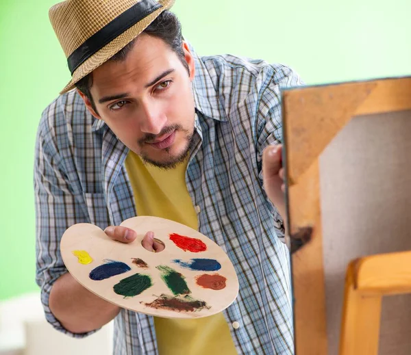 Young male artist working on new painting in his studio