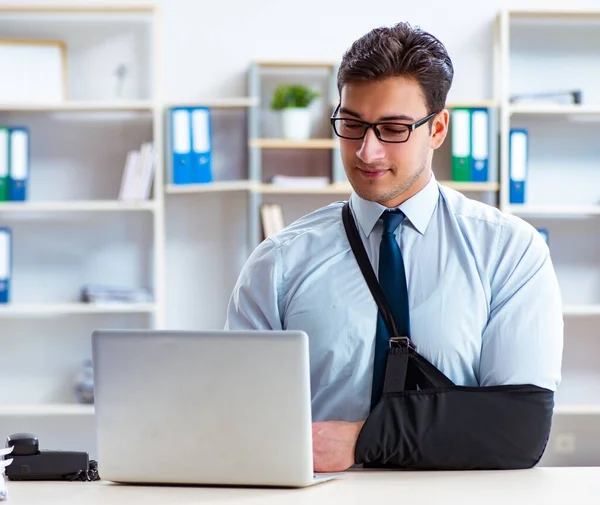 Бизнесмен со сломанной рукой работает в офисе — стоковое фото