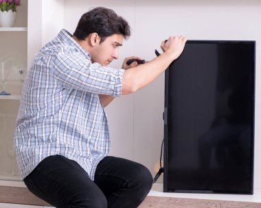 Evdeki bozuk televizyonu tamir eden adam.