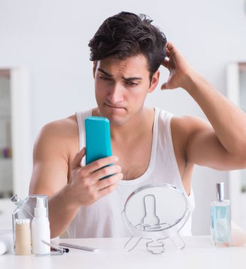 Genç yakışıklı adam aynaya bakıyor.