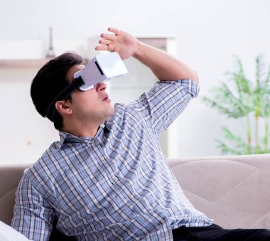 Adam evde sanal gerçeklik gözlüğü izliyor.