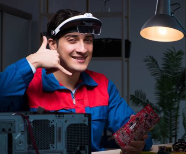 Bilgisayar uzmanı gece geç saatlerde bilgisayarı tamir ediyor.