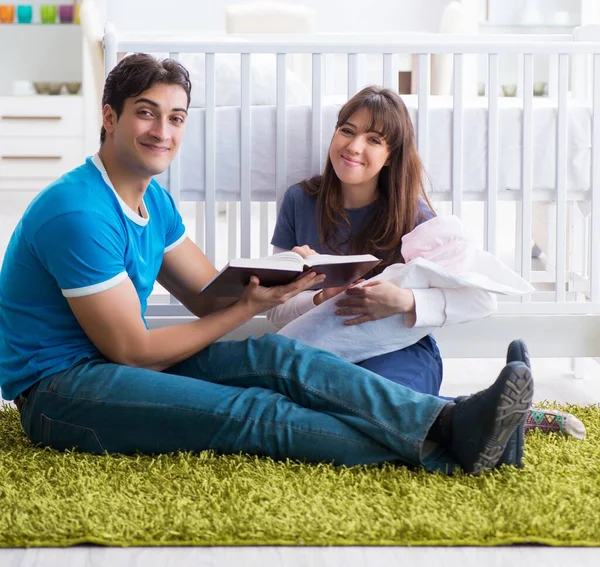 Jonge ouders met hun pasgeboren baby zittend op het tapijt — Stockfoto