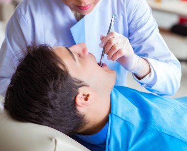 Kadın dişçi ve erkek hasta hastanede.