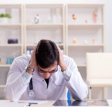 Genç doktor ofiste oturuyor.