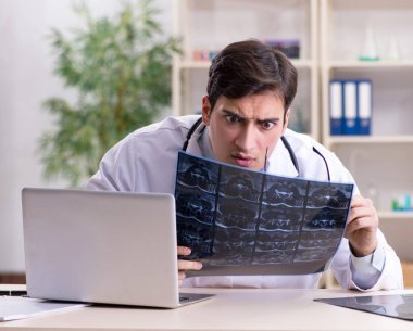 Genç doktor klinikteki röntgen görüntülerine bakıyor.