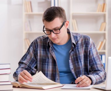 Okul sınavlarına kitaplarla hazırlanan genç bir öğrenci.