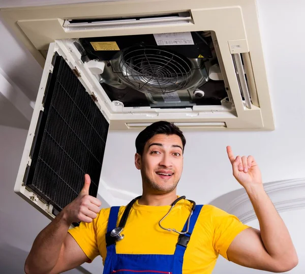 Repairman repairing ceiling air conditioning unit