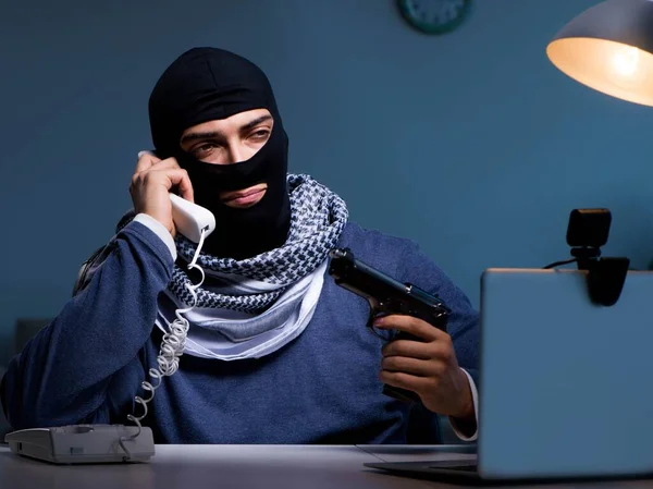 Терористичний грабіжник з пістолетом, що працює за комп'ютером — стокове фото