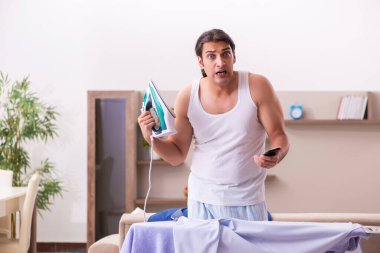 Genç erkek çalışan sabah ütü yapıyor.