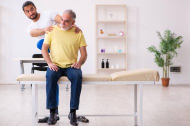 Yaşlı erkek hasta, genç erkek doktor masörünü ziyaret ediyor.