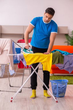 Genç adam evde ütü yapıyor.