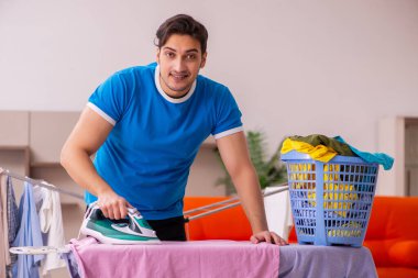 Genç adam evde ütü yapıyor.