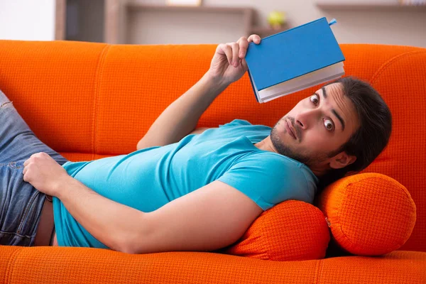 Junge männliche Studentin sitzt auf dem orangefarbenen Sofa — Stockfoto