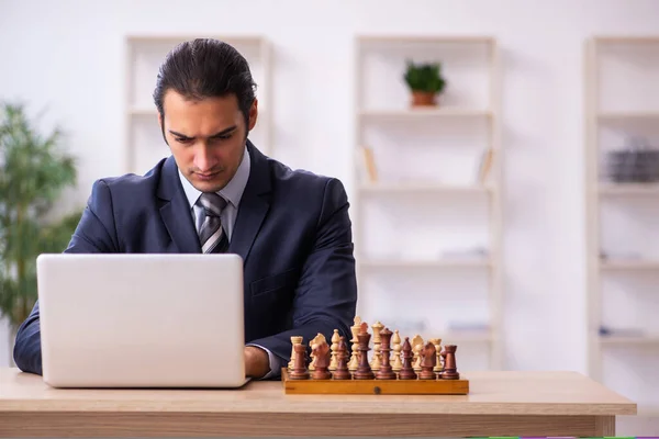 Joven empleado masculino jugando ajedrez en el lugar de trabajo — Foto de Stock