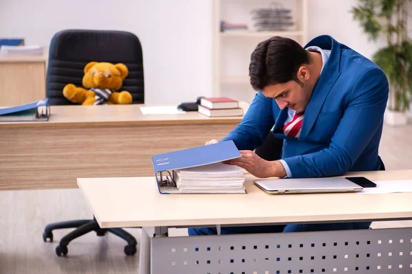 Jong mannelijk werknemer en zijn speelgoed beer baas in grappig concept — Stockfoto