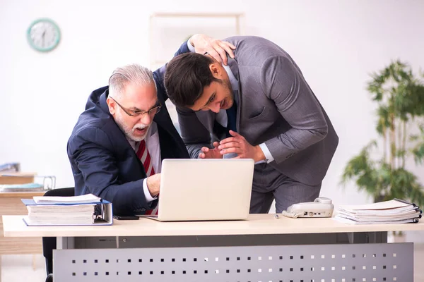 Old boss and young male employee working in the office — Stock Photo, Image