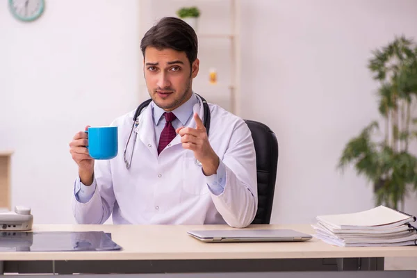 Genç erkek doktor klinikte kahve içiyor. — Stok fotoğraf