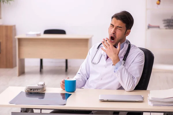 Young male doctor drinking coffee in the clinic