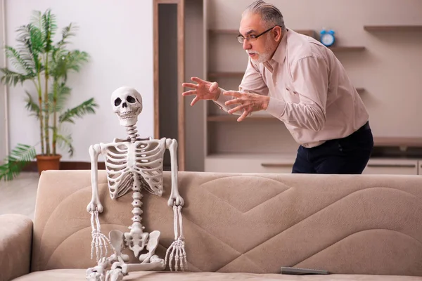 Oude man zittend op de bank met het vrouwelijke skelet — Stockfoto