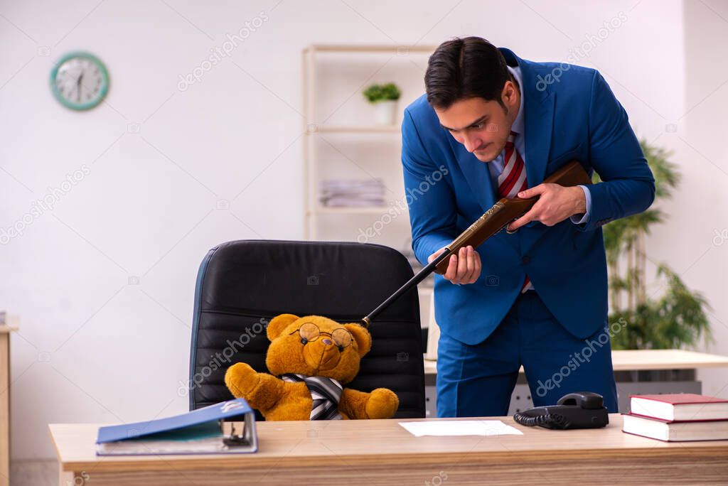 Young male employee and his toy bear boss in funny concept