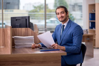 Ofisteki aşırı işten memnun olmayan genç bir erkek işçi.