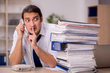 Genç bir erkek çalışan ve ofiste bir sürü iş var.