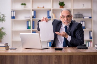 Ofiste çalışan yaşlı bir erkek.