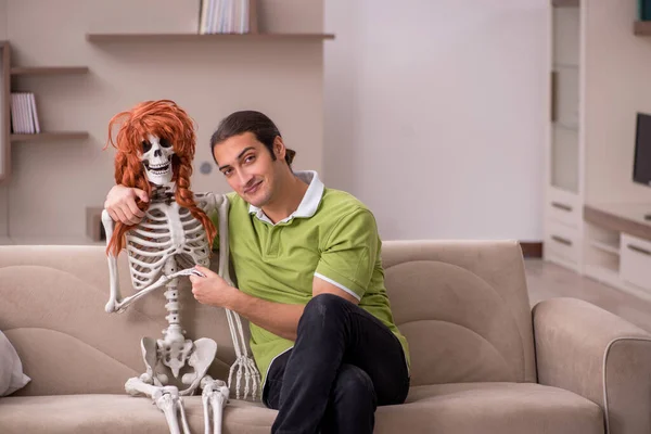 Jeune homme assis sur le canapé avec squelette féminin — Photo