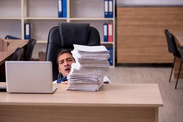 Jonge mannelijke werknemer ongelukkig met overmatig werk in het kantoor — Stockfoto