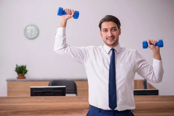 Jovem empresário empregado fazendo exercícios esportivos no local de trabalho — Fotografia de Stock