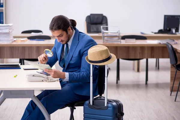 Young male employee preparing for trip in the office