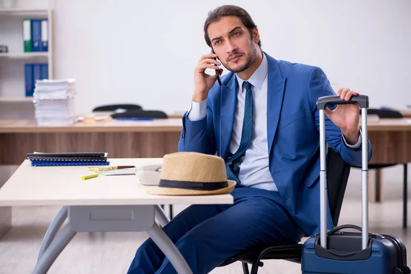 Young male employee preparing for trip in the office