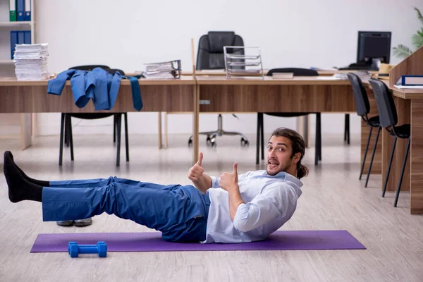 Mladý muž zaměstnanec dělá sportovní cvičení během přestávky — Stock fotografie