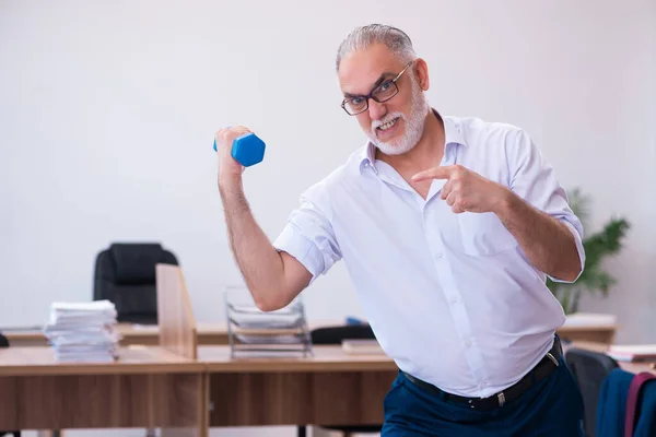 Oude zakenman werknemer doet sport oefeningen in het kantoor — Stockfoto