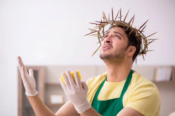 Jonge mannelijke aannemer draagt stekelige krans op het hoofd schoonmaken th — Stockfoto