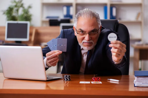Oude mannelijke werknemer speelkaarten op de werkplek — Stockfoto