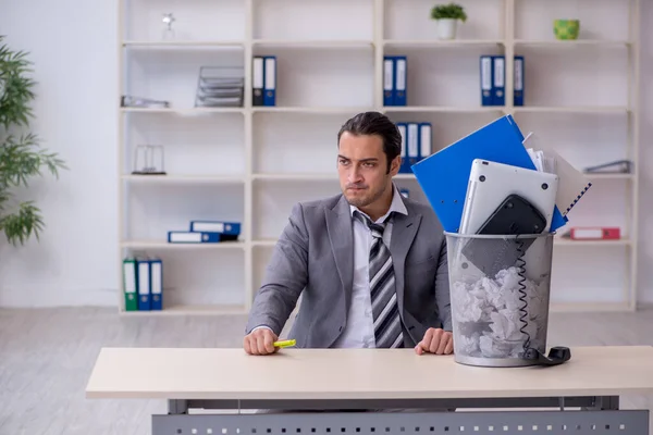 Fired young businessman with recycle bin in the office