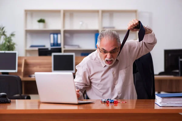 Old male employee in gambling concept at workplace — Stock Photo, Image