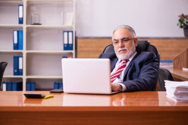 Eski erkek çalışan ofiste oturuyor.